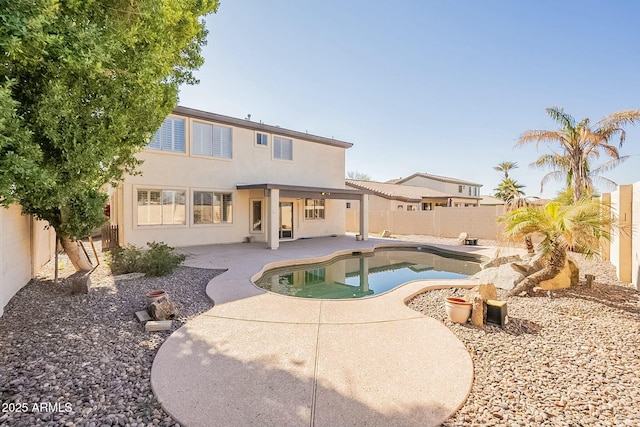 back of property with a patio area and a fenced in pool