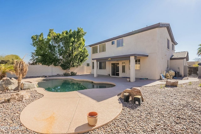 rear view of house with a fenced in pool and a patio