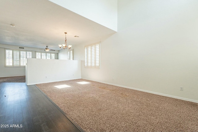 empty room featuring ceiling fan with notable chandelier and dark wood-type flooring