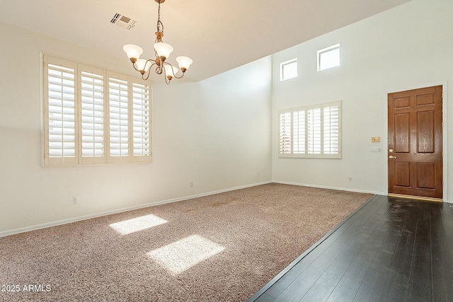 spare room featuring a chandelier and dark colored carpet