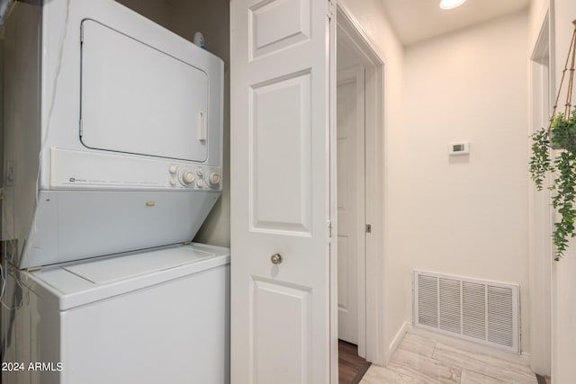 laundry room featuring light hardwood / wood-style flooring and stacked washer / dryer