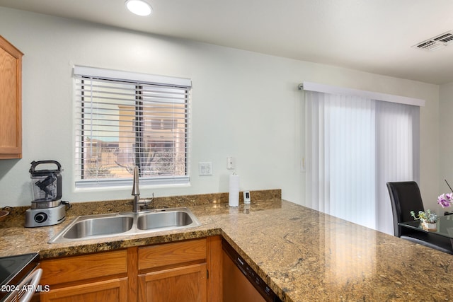 kitchen featuring stainless steel dishwasher, sink, range, and stone counters