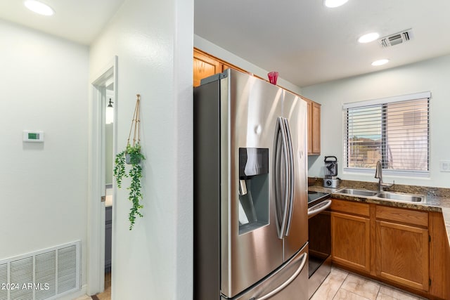 kitchen with sink, light tile floors, stainless steel fridge with ice dispenser, stove, and dark stone countertops