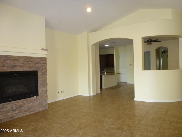 6687 S Banning St, Gilbert, AZ 85298 - unfurnished living room with vaulted ceiling, a stone fireplace, tile patterned floors, ceiling fan, and arched walkways