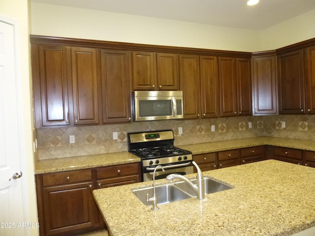 6687 S Banning St, Gilbert, AZ 85298 - kitchen featuring appliances with stainless steel finishes, light stone countertops, a sink, a center island with sink, and tasteful backsplash