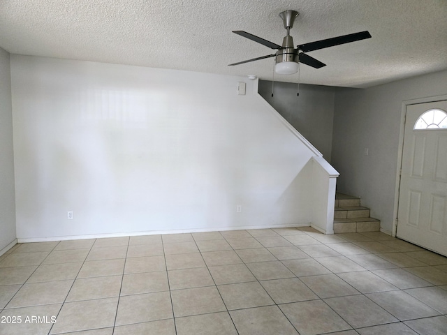 entryway with a textured ceiling, a ceiling fan, stairs, and light tile patterned floors