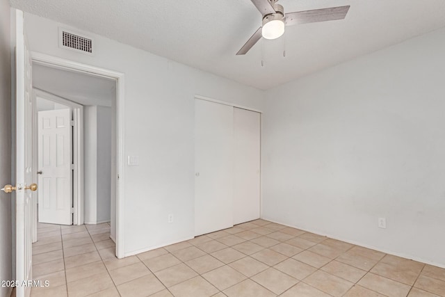 unfurnished bedroom featuring light tile patterned floors, a closet, and a ceiling fan