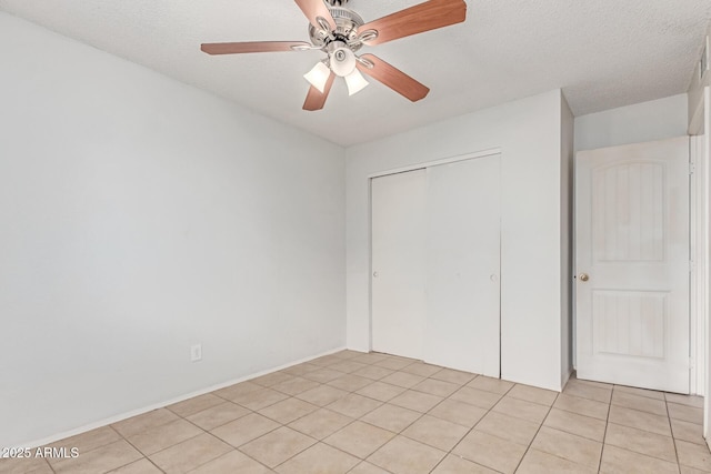 unfurnished bedroom featuring a closet, light tile patterned floors, a ceiling fan, and a textured ceiling