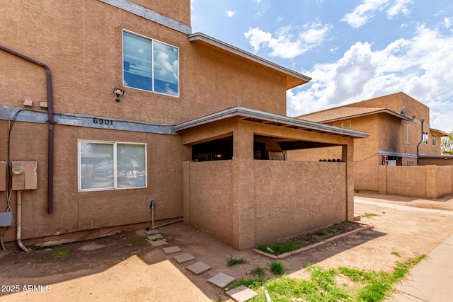 view of property exterior with stucco siding and fence