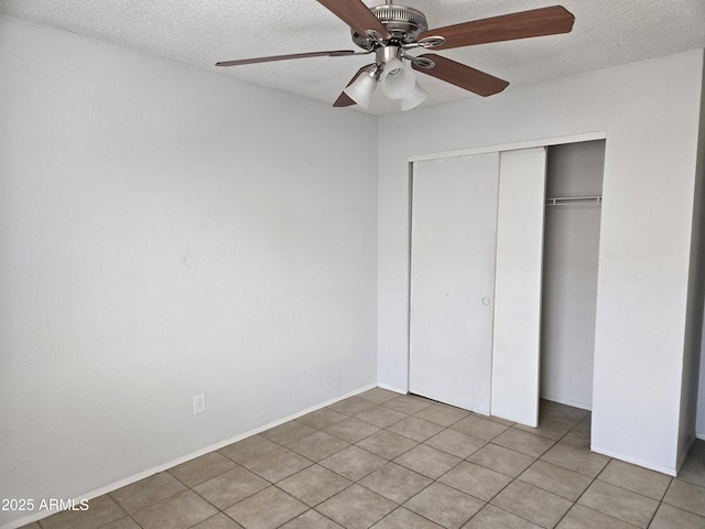unfurnished bedroom with a closet, a textured ceiling, a ceiling fan, and tile patterned floors