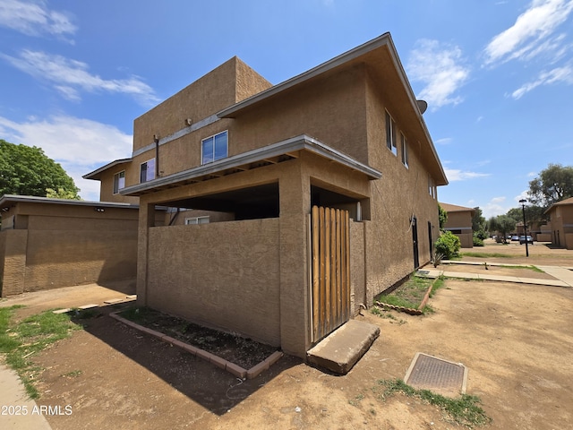 rear view of house with stucco siding and fence