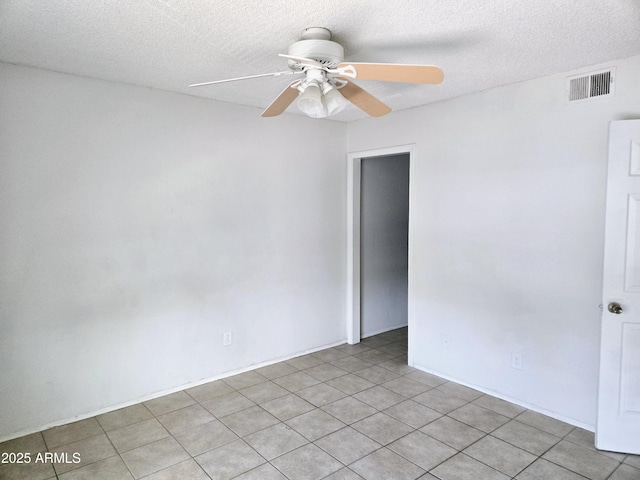 unfurnished room with ceiling fan, light tile patterned floors, and a textured ceiling