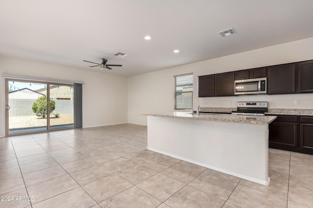 kitchen with visible vents, an island with sink, light stone countertops, stainless steel appliances, and a sink