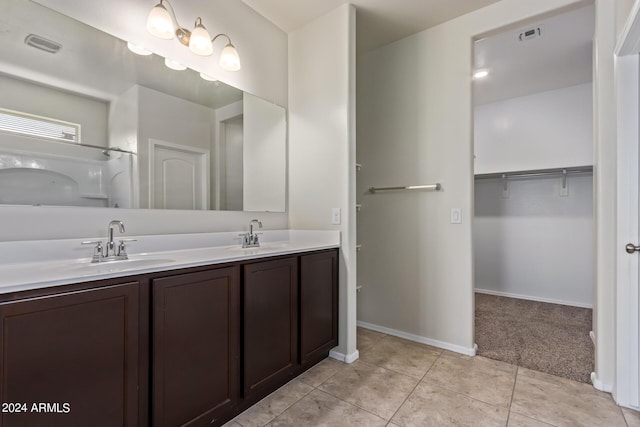 full bathroom with a sink, double vanity, tile patterned flooring, and a walk in closet