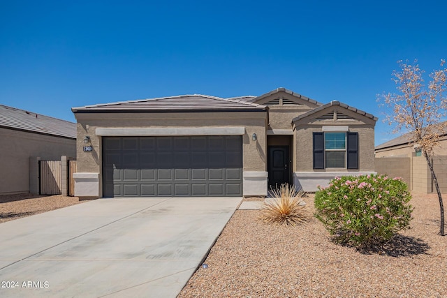 view of front facade with concrete driveway, a tiled roof, an attached garage, and stucco siding