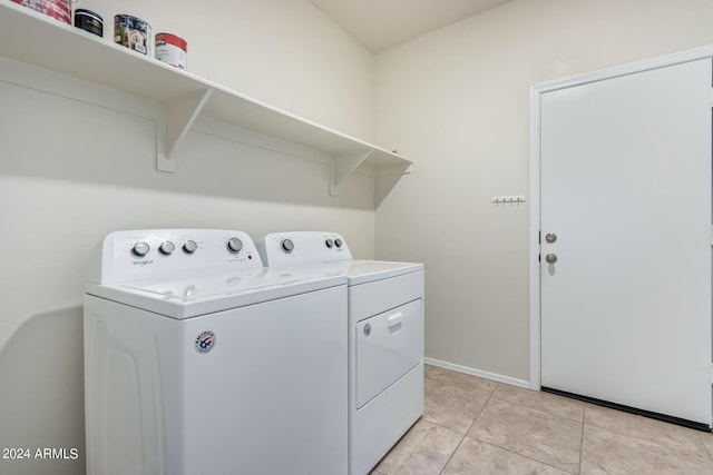 clothes washing area featuring light tile patterned floors, laundry area, washing machine and dryer, and baseboards