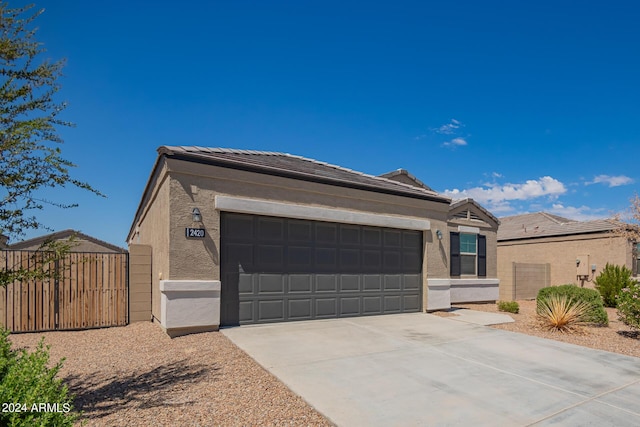 ranch-style home featuring an attached garage, fence, a tile roof, driveway, and stucco siding