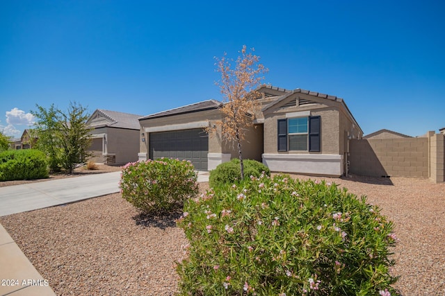 ranch-style home with driveway, an attached garage, fence, and stucco siding