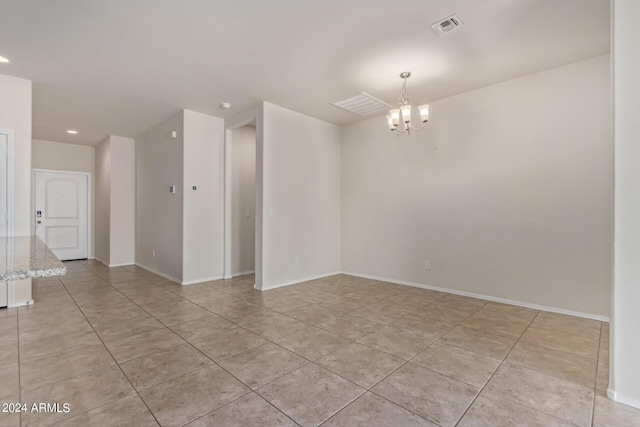 empty room with light tile patterned floors, baseboards, visible vents, and a chandelier