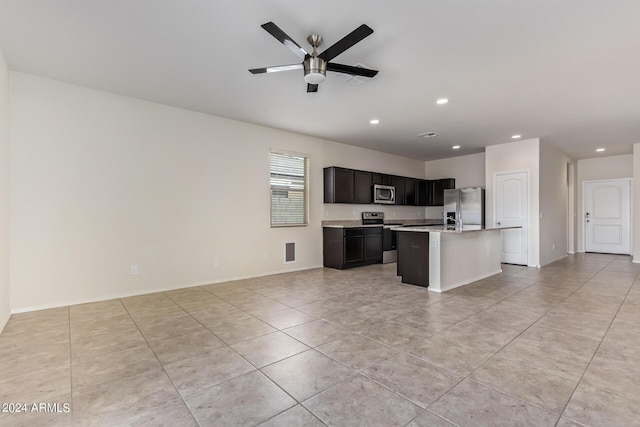 kitchen with a center island with sink, a ceiling fan, appliances with stainless steel finishes, open floor plan, and light countertops