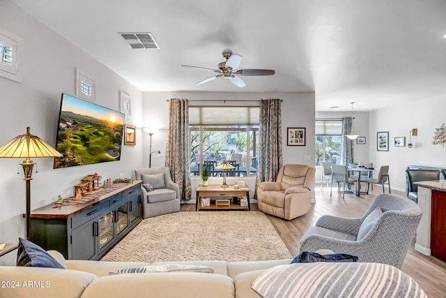 living room with light wood-type flooring, plenty of natural light, and ceiling fan