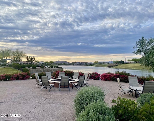 patio terrace at dusk with an outdoor fire pit and a water and mountain view