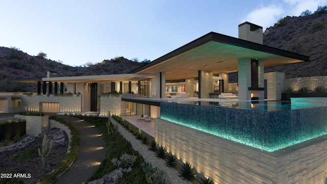 back house at dusk featuring a patio area and a mountain view