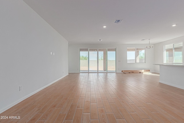 spare room featuring light wood-type flooring and a notable chandelier