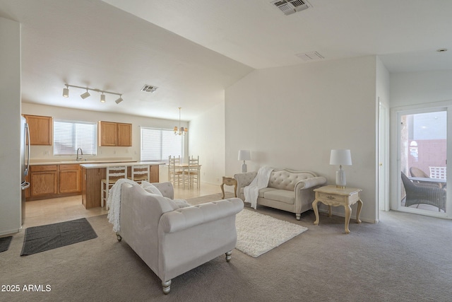 living area with light carpet, visible vents, vaulted ceiling, and a notable chandelier