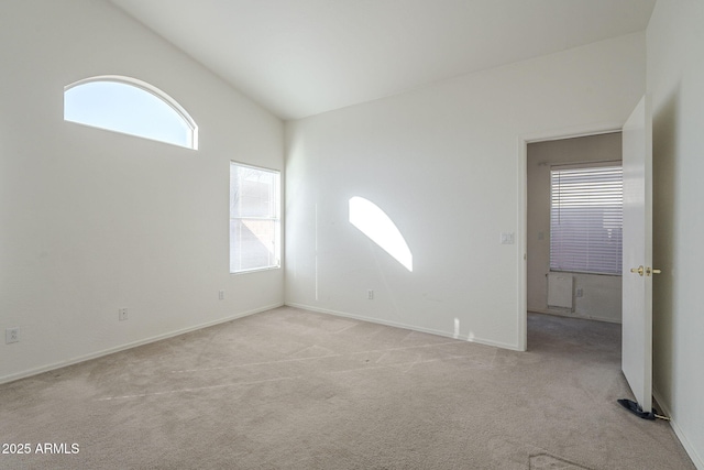 spare room featuring high vaulted ceiling and light carpet