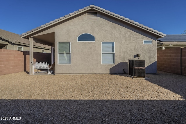 back of house with fence, a tiled roof, and stucco siding