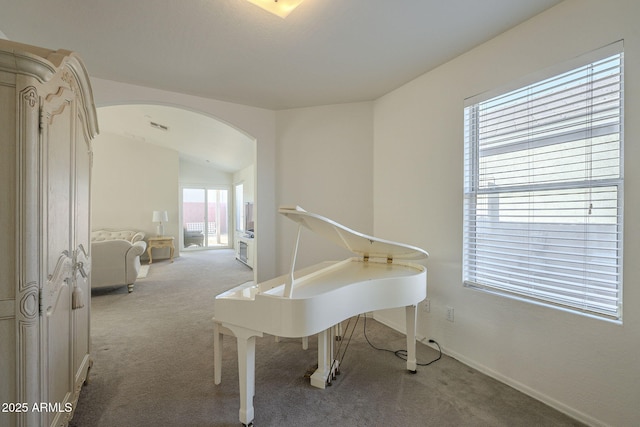 sitting room with arched walkways, carpet flooring, and baseboards