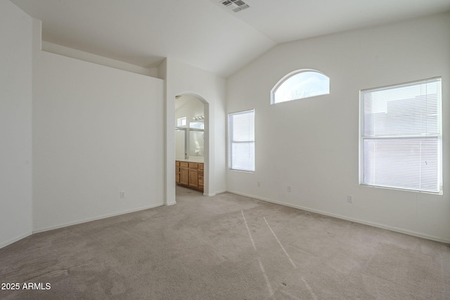 empty room featuring visible vents, vaulted ceiling, and light colored carpet