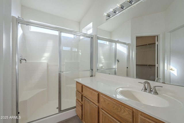 full bathroom with a spacious closet, a stall shower, and vanity