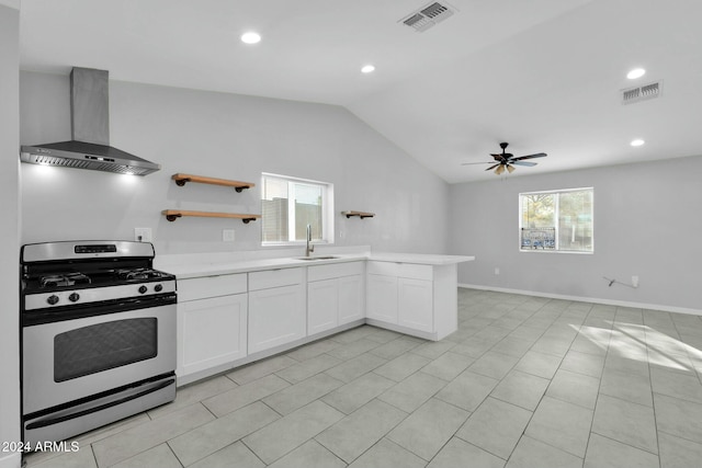 kitchen with white cabinets, sink, vaulted ceiling, stainless steel gas range, and wall chimney exhaust hood