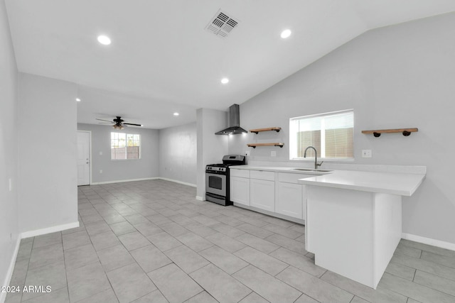 kitchen with lofted ceiling, wall chimney range hood, gas range, ceiling fan, and white cabinetry