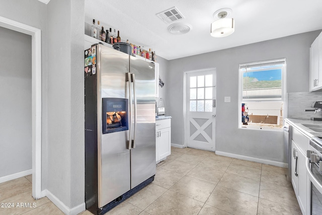 kitchen featuring backsplash, stainless steel fridge, white cabinets, and light tile patterned floors