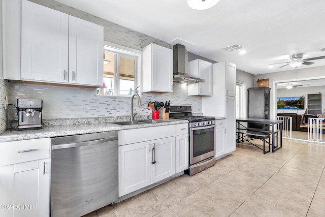 kitchen with white cabinetry, sink, stainless steel appliances, and wall chimney range hood