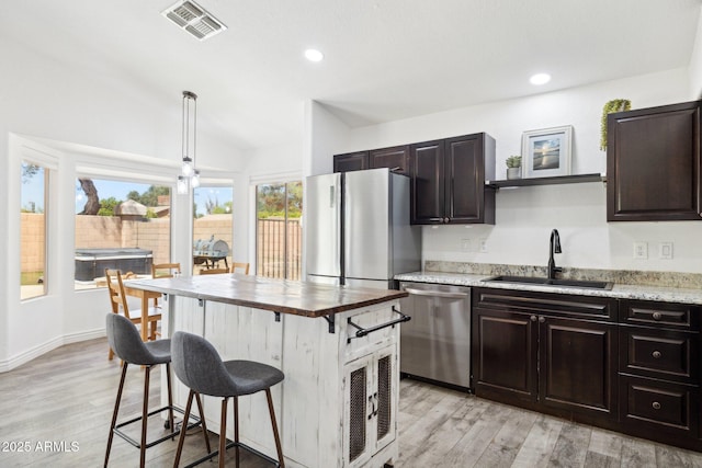 kitchen with visible vents, a sink, light wood finished floors, a breakfast bar, and stainless steel appliances