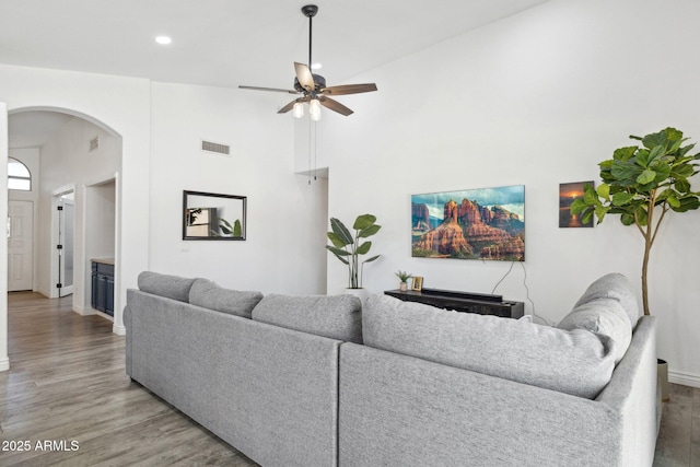 living room with arched walkways, a ceiling fan, recessed lighting, wood finished floors, and visible vents