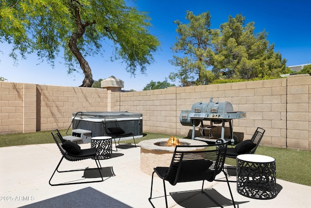 view of patio / terrace featuring a hot tub, a fenced backyard, area for grilling, and an outdoor fire pit
