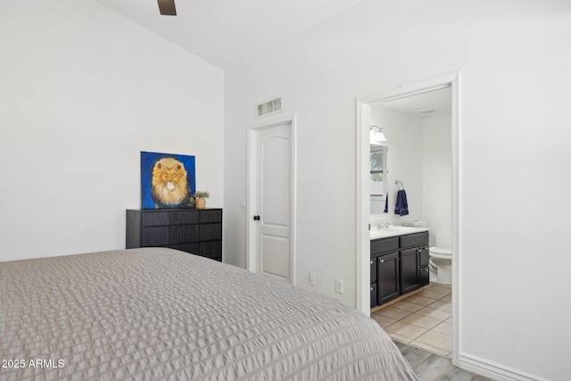 bedroom featuring a sink, ensuite bathroom, light wood finished floors, and visible vents