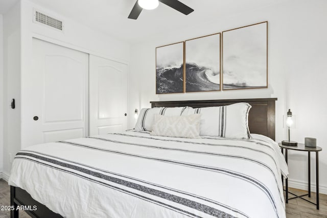 bedroom featuring baseboards, a closet, wood finished floors, and visible vents