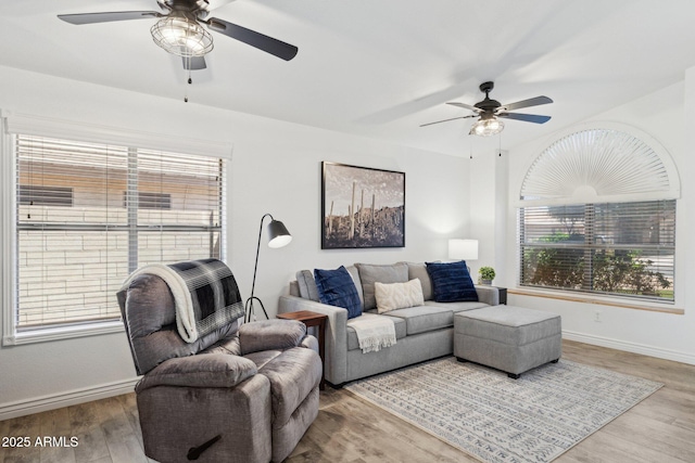 living area with a ceiling fan, baseboards, and wood finished floors