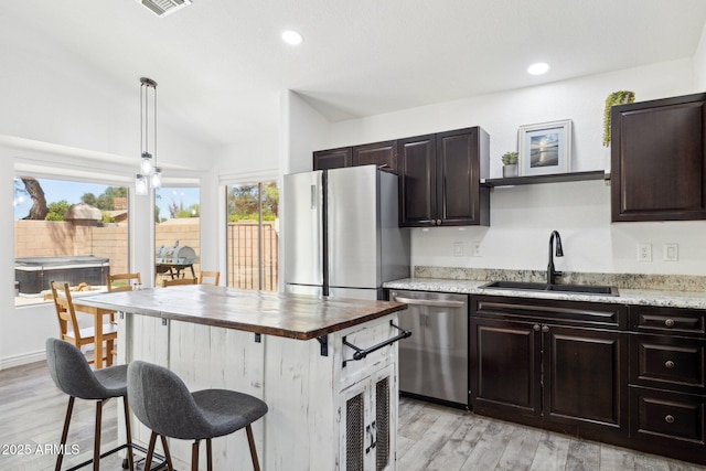 kitchen featuring a sink, appliances with stainless steel finishes, a breakfast bar, and light wood finished floors