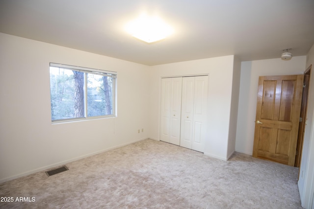 unfurnished bedroom with light colored carpet and a closet