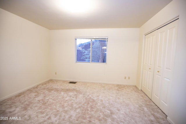 unfurnished bedroom featuring a closet and light colored carpet