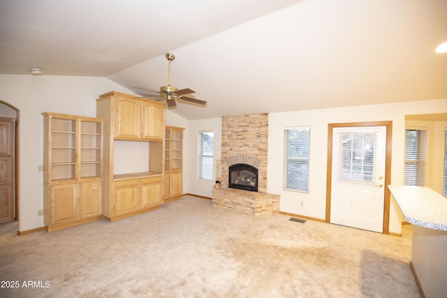 unfurnished living room featuring ceiling fan, a fireplace, light carpet, and lofted ceiling