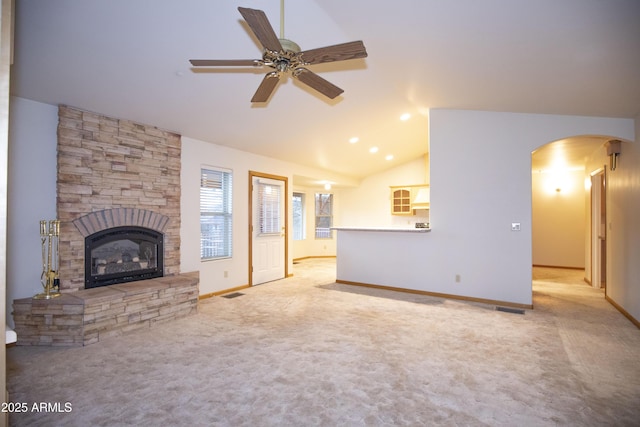 unfurnished living room with a stone fireplace, ceiling fan, light carpet, and lofted ceiling