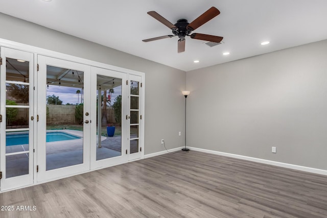 spare room with wood finished floors, visible vents, baseboards, ceiling fan, and french doors